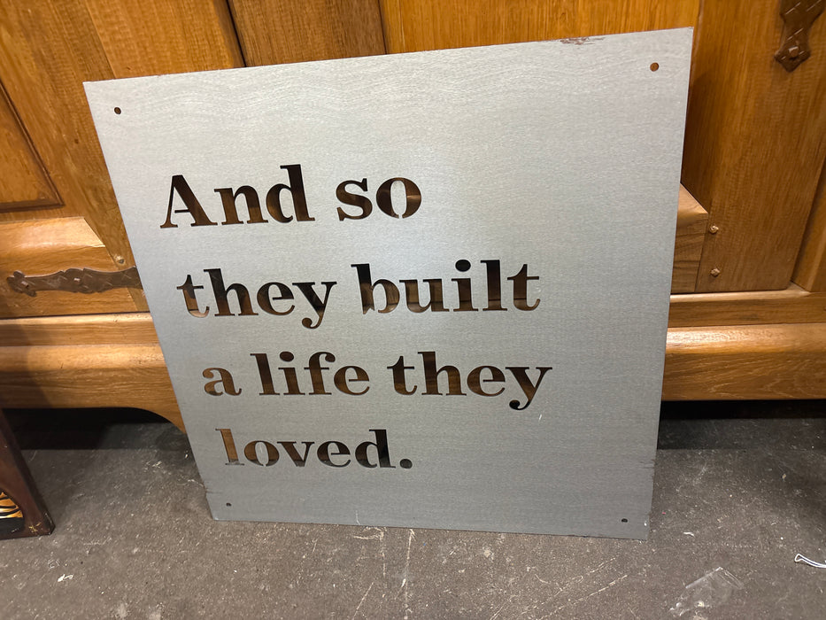 SIMPLE BLACK METAL PANEL "AND SO THEY BUILT A LIFE THEY LOVED" - SIGNED JIMMY DON