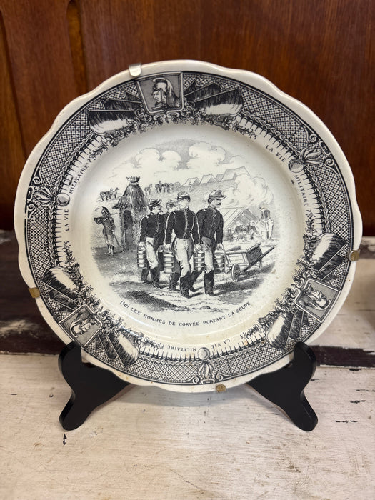 SMALL FRENCH SARREGUEMINES TRANSFERWARE MILITARY PLATE OF SOLIDERS WALKING THROUGH CAMP “LES HOMMES DE CORVÉE PORTANT LA SOUPE”
