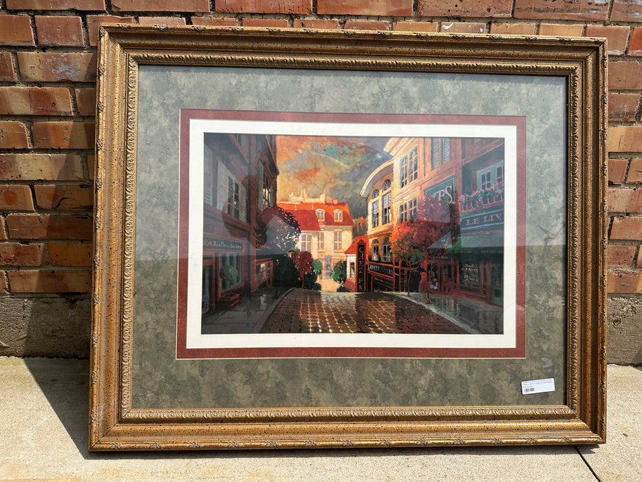 LARGE COLORFUL PRINT OF SHOPS ON HILL WITH COBBLESTONE ROAD