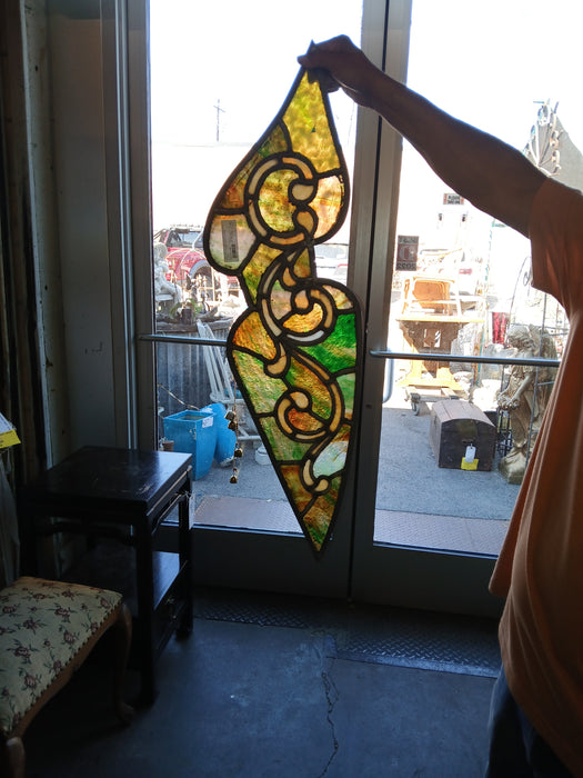 SMALL SHAPED STAINED GLASS PANEL WITH GREEN AND YELLOW GREEN GLASS AND SCROLLS