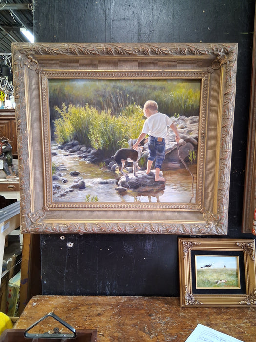 FRAMED OIL PAINTING OF A BOY AND DOG BY A STREAM SIGNED SHERRY HERRINGTON CIRCA 1997