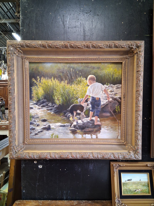 FRAMED OIL PAINTING OF A BOY AND DOG BY A STREAM SIGNED SHERRY HERRINGTON CIRCA 1997
