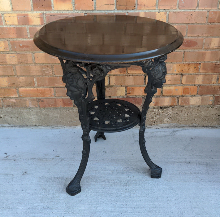 BLACK PAINTED MAHOGANY TOP CAST IRON PUB TABLE WITH FIGURAL MASKS