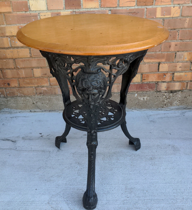 LIGHT MAHOGANY TOP CAST IRON PUB TABLE WITH FIGURAL MASKS