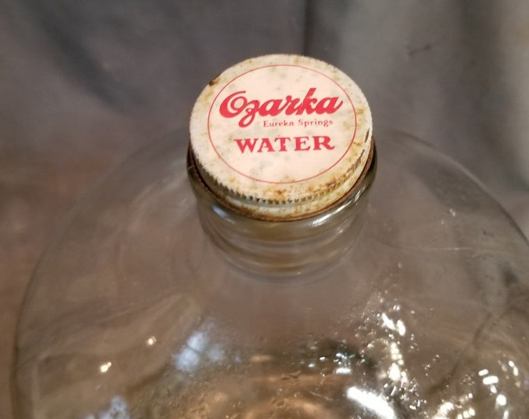 1930'S EMBOSSED OZARKA GLASS WATER BOTTLE IN ORIGINAL GRATE