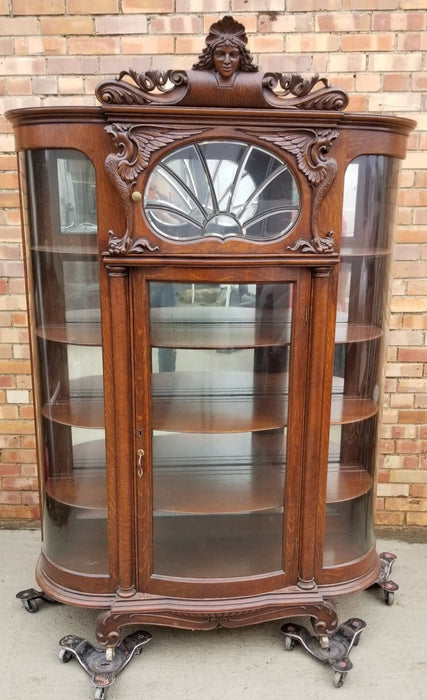 AMERICAN CURVED GLASS DISPLAY CASE WITH GRIFFINS ANS LADY HEAD PEDIMENT