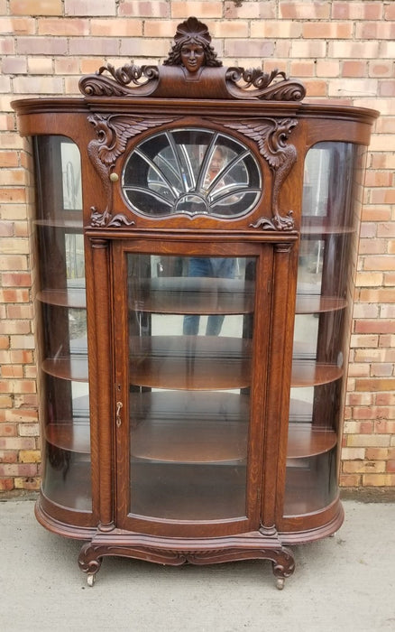 AMERICAN CURVED GLASS DISPLAY CASE WITH GRIFFINS ANS LADY HEAD PEDIMENT