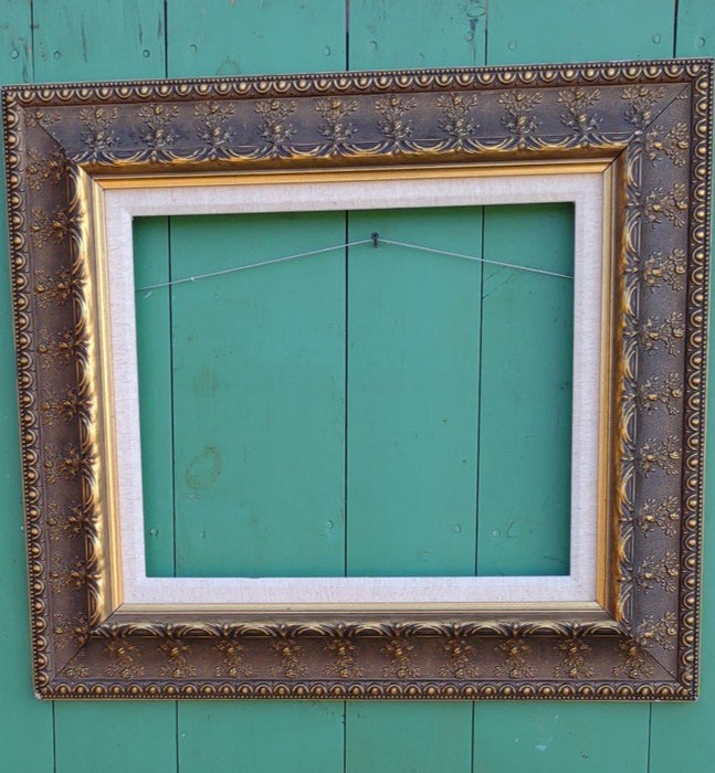 ORNATE GOLD FRAME WITH FLORAL MOTIF AND LINEN LINER