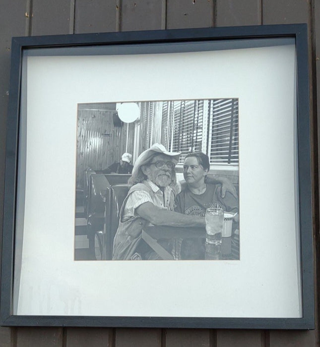 FRAMED PHOTO OF BEARDED MAN AND A WOMAN IN A RESTAURANT