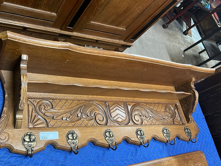 SHIELD AND FOLIATE  CARVED OAK WALL SHELF WITH SHIELD AND TWO CHILDREN ON HOOKS