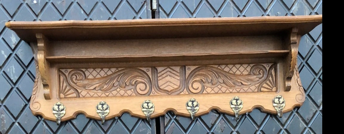 SHIELD AND FOLIATE  CARVED OAK WALL SHELF WITH SHIELD AND TWO CHILDREN ON HOOKS