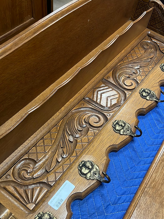 SHIELD AND FOLIATE  CARVED OAK WALL SHELF WITH SHIELD AND TWO CHILDREN ON HOOKS