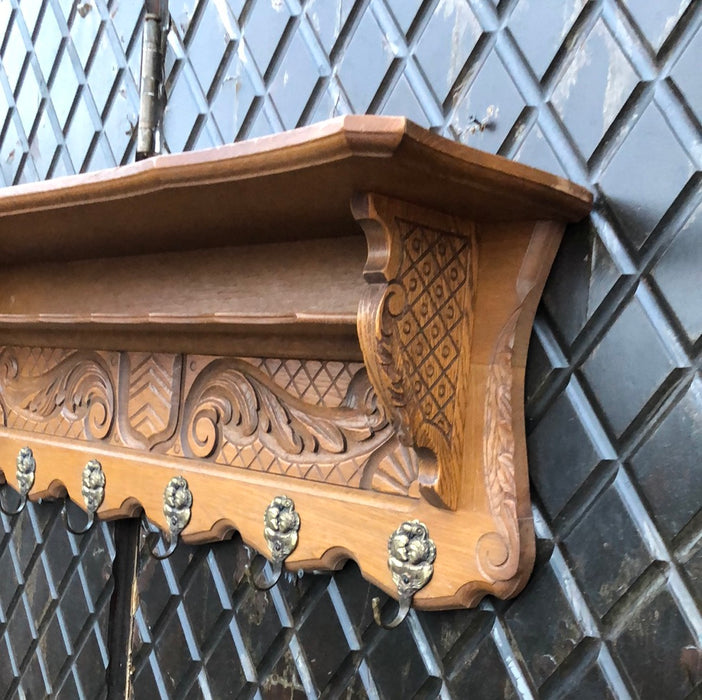 SHIELD AND FOLIATE  CARVED OAK WALL SHELF WITH SHIELD AND TWO CHILDREN ON HOOKS