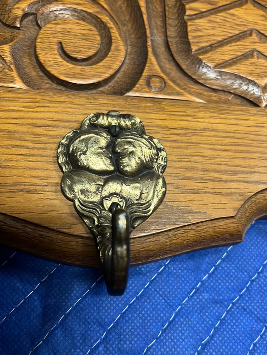 SHIELD AND FOLIATE  CARVED OAK WALL SHELF WITH SHIELD AND TWO CHILDREN ON HOOKS